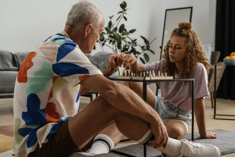 A resident playing chess with his granddaughter