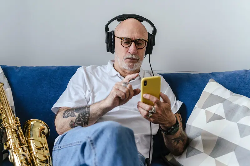 A resident choosing a song on his phone, saxophone beside him