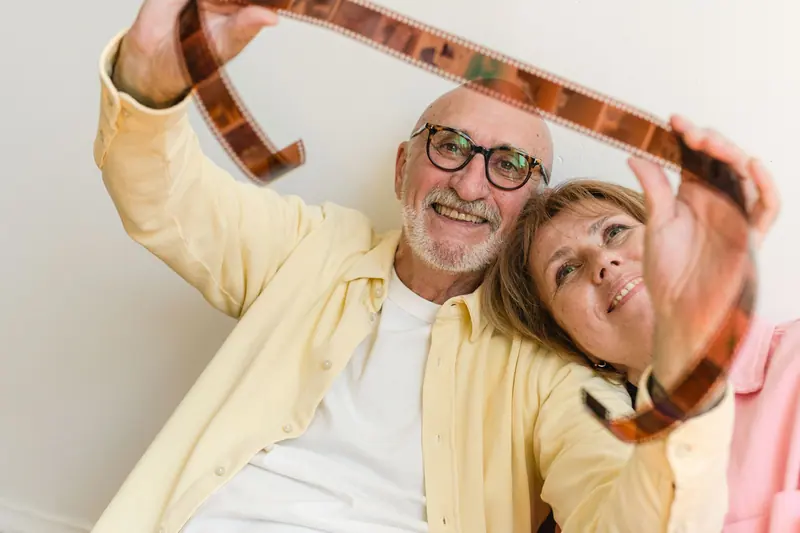 A couple laughing as they hold old film negatives up to the light