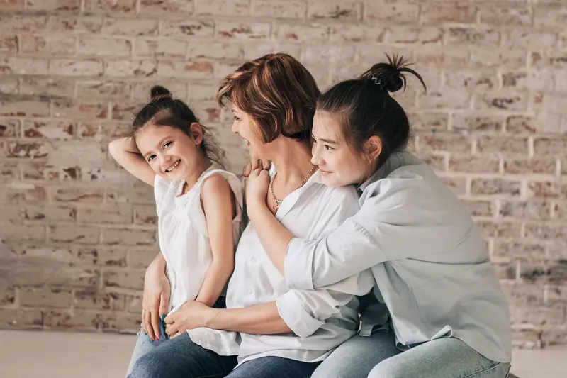 A resident and her granddaughters laughing together on visiting day