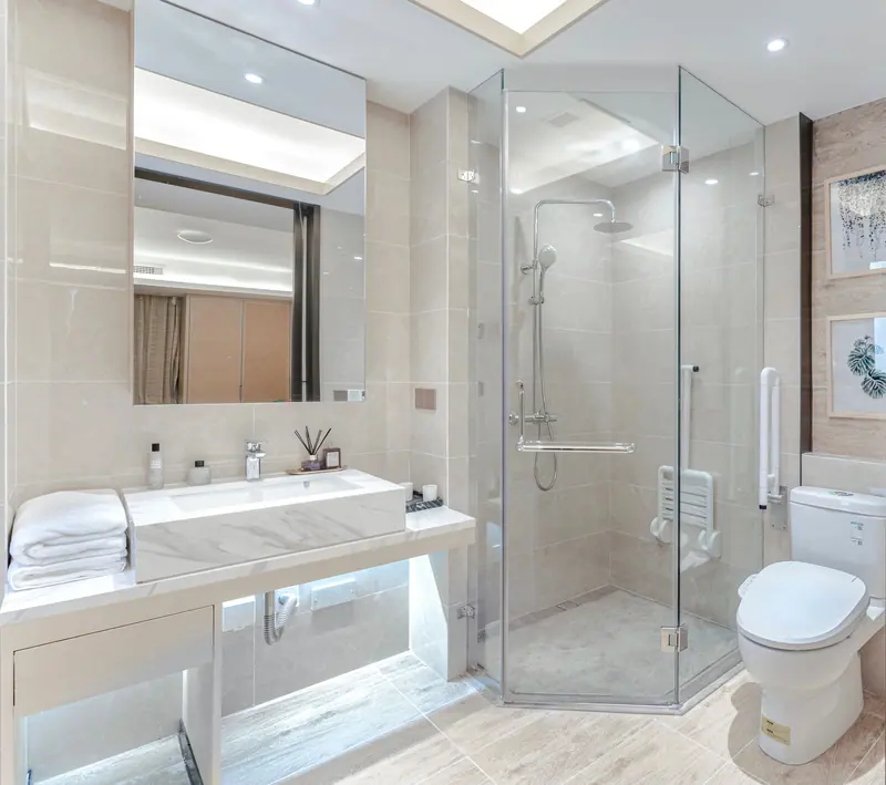 A stylish bathroom featuring a glass shower, marble sink, and elegant decor.
