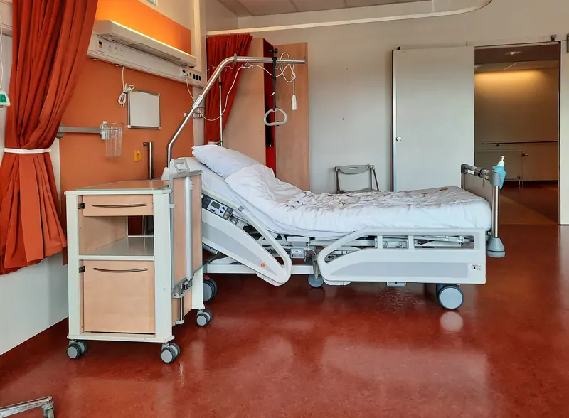 A clean and modern hospital room equipped with an adjustable bed and medical equipment.