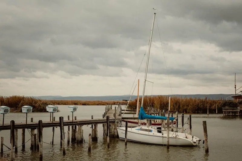 A sailboat tied at the old wooden pier on a gray morning