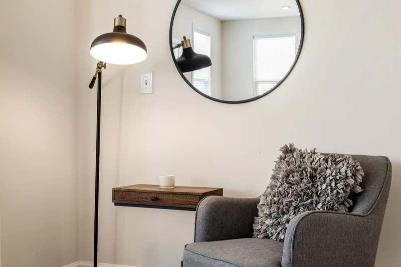 A quiet reading corner with a gray armchair and lamp