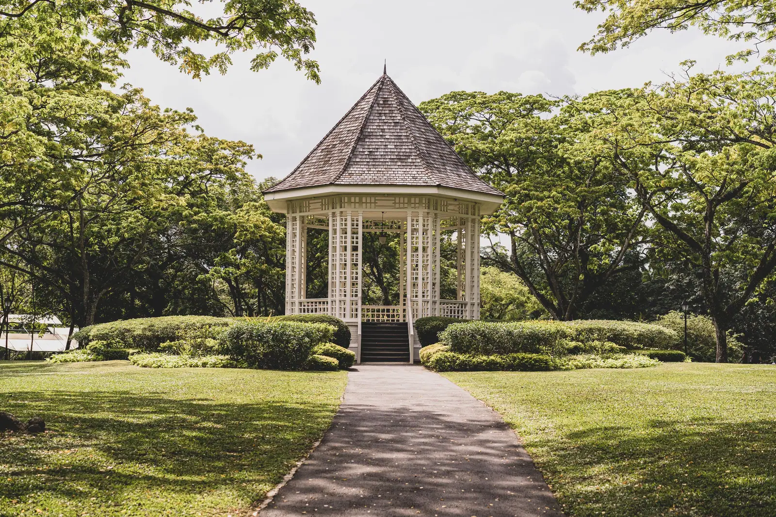 A picturesque gazebo surrounded by lush greenery in a tranquil summer park setting.