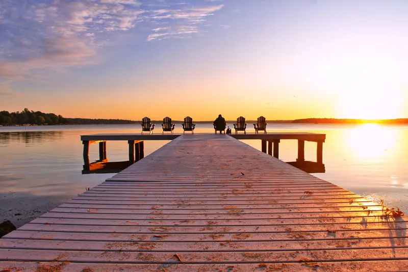 A wooden dock reaching into a lake at sunset