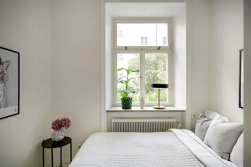 Bright and inviting minimalist bedroom with a large window and stylish decor.