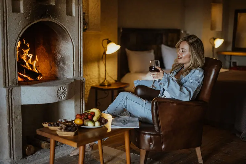 A resident settling into a leather chair by the lobby fireplace with a glass of wine