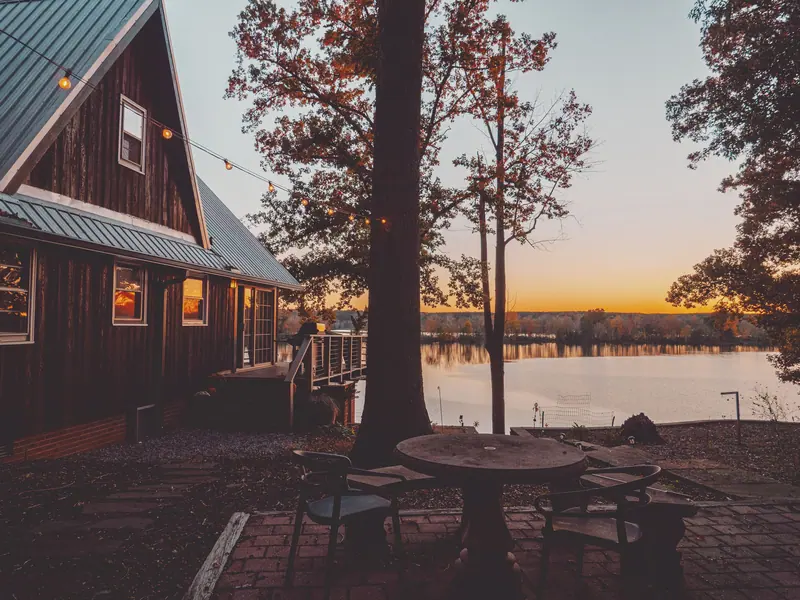 A cottage at dusk with the lake behind it