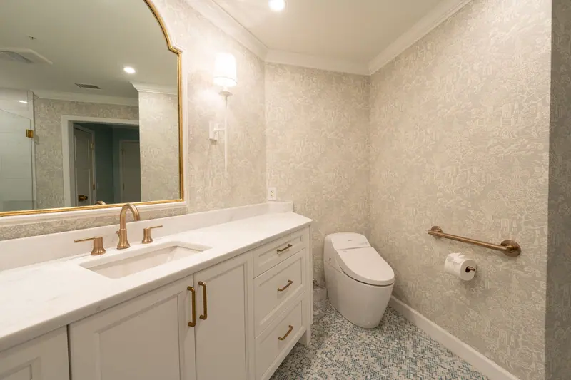 Stylish bathroom design featuring a vanity, mirror, modern toilet, and patterned wallpaper.