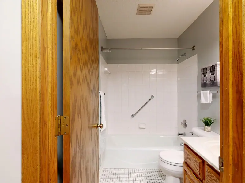 Bright bathroom with bathtub, wooden door, and white decor.