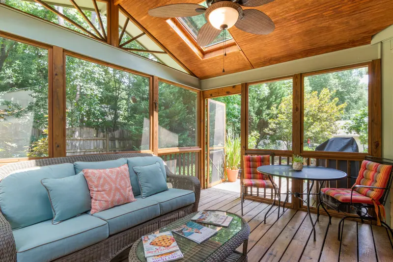 The screened porch with blue cushions and a ceiling fan