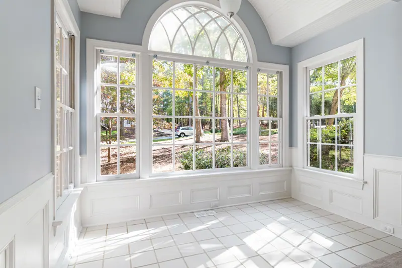 The sunroom's arched window looking out over the trees