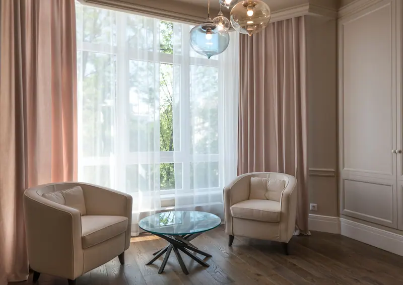 A bright living room with modern armchairs and a glass table, exuding elegance and comfort.