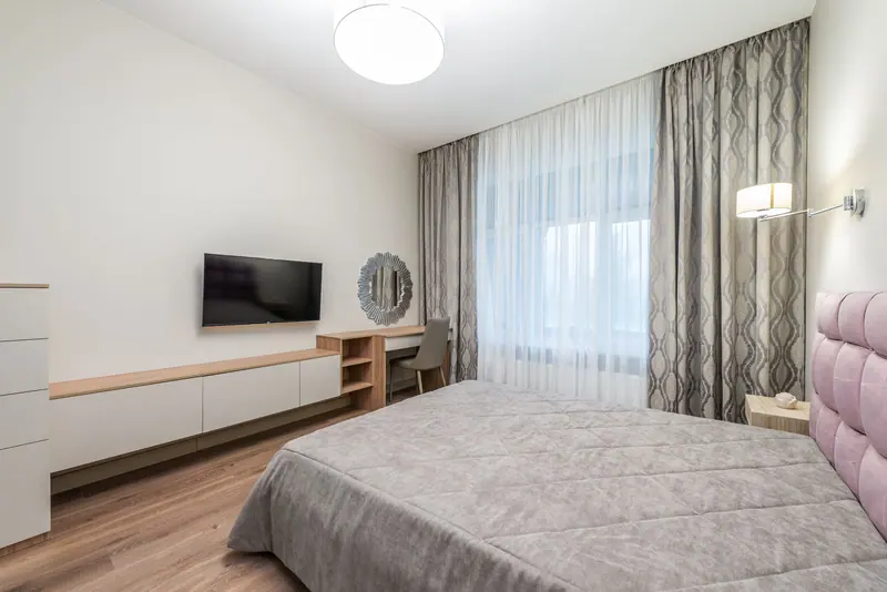 Spacious modern bedroom with minimalist decor including a bed, TV, and stylish furniture.
