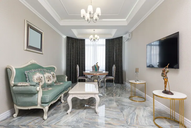 A sitting room with a sage sofa and marble floors in a Camellia cottage