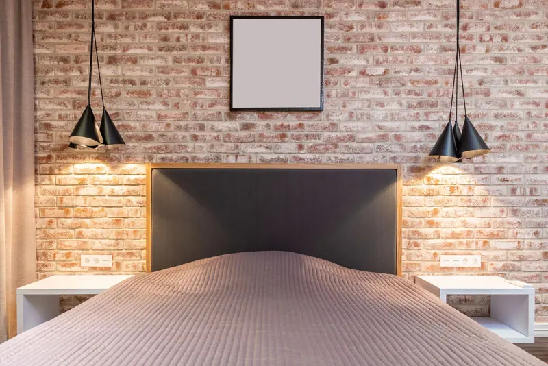 Contemporary bedroom featuring brick wall, pendant lights, and minimalist design.