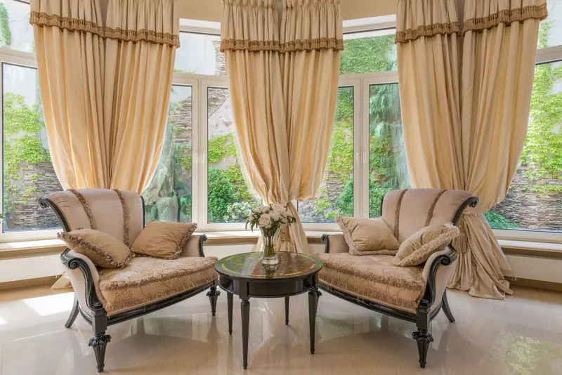 A sitting room with tall windows and draped curtains