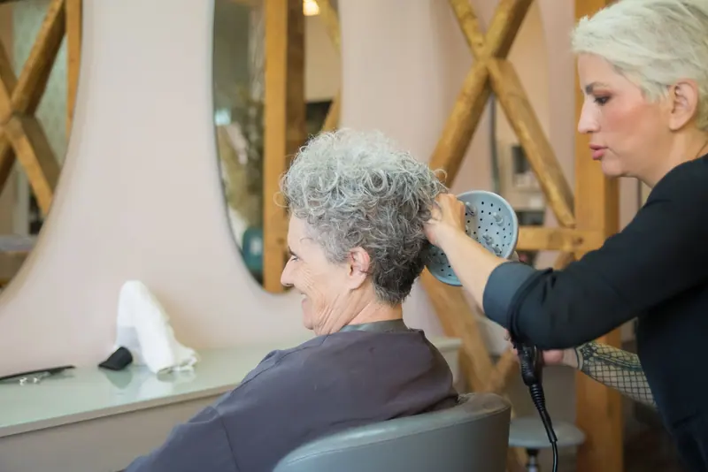 A stylist finishing a resident's cut in the salon