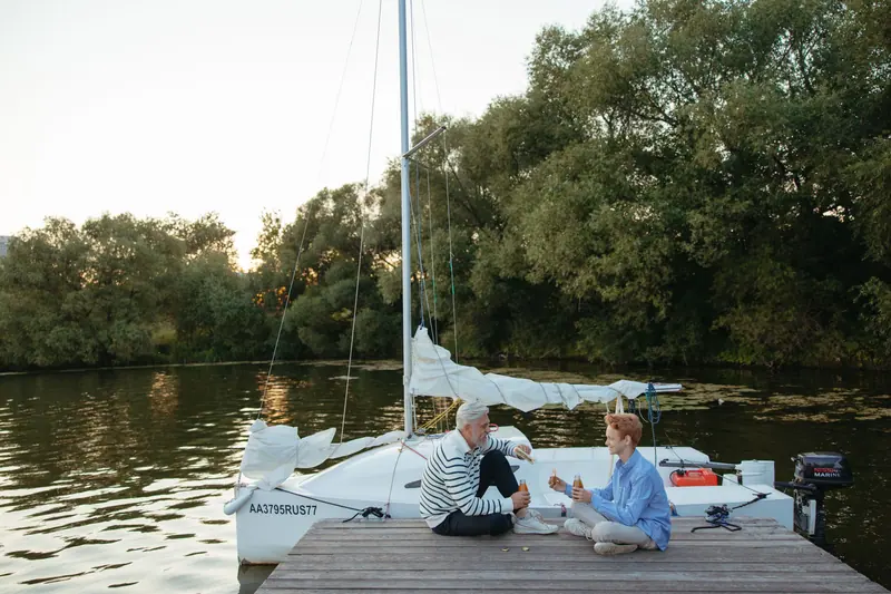 Two residents sharing a picnic on the dock beside their sailboat