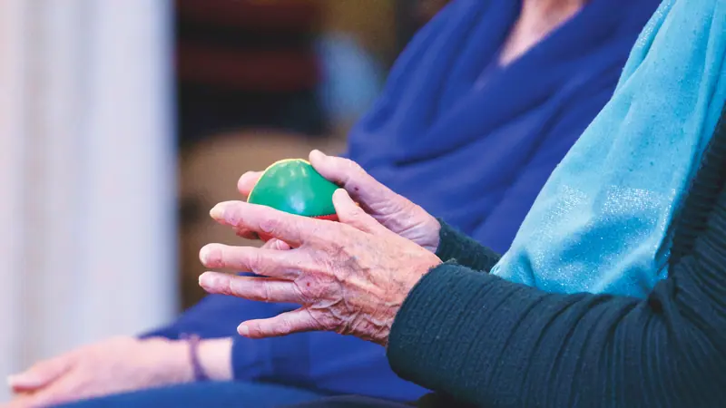 A guest squeezing a therapy ball