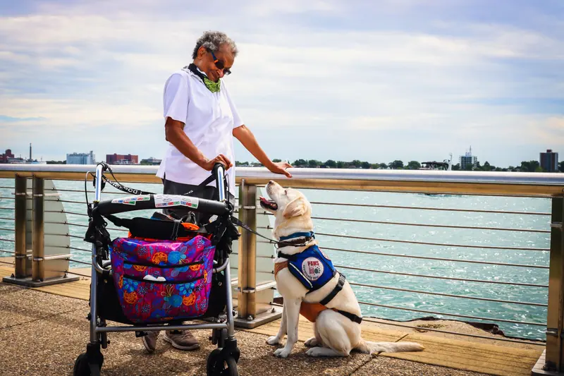 A resident walking her rollator alongside her therapy dog