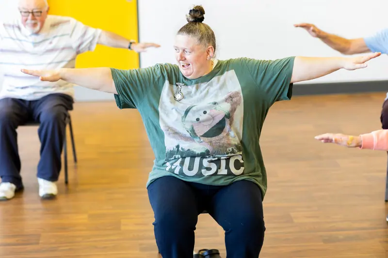 A seated exercise class stretching their arms wide