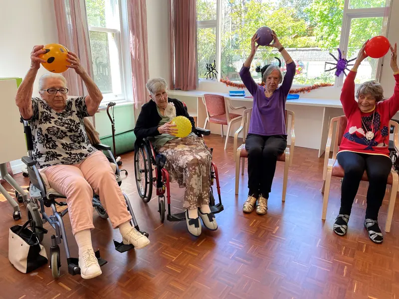 Residents raising exercise balls overhead during the morning chair-exercise class