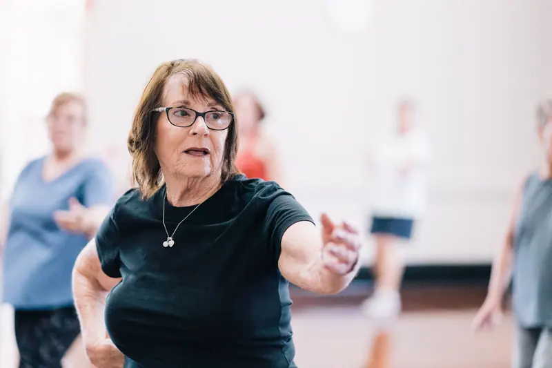 A resident working on balance with her arms out