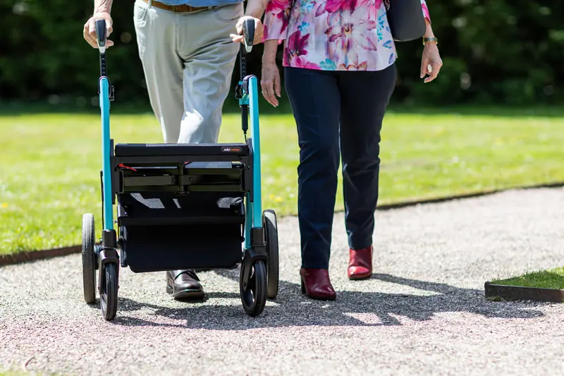 A woman walking her rollator alongside her husband in the park