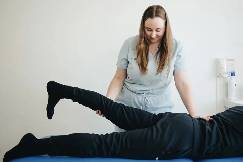 A therapist lifting a patient's leg on the treatment table