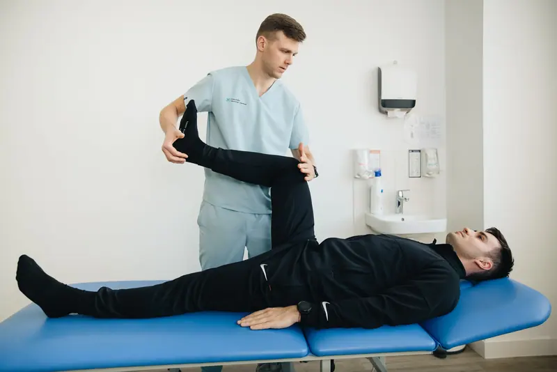 A therapist stretching a patient's leg on the treatment table