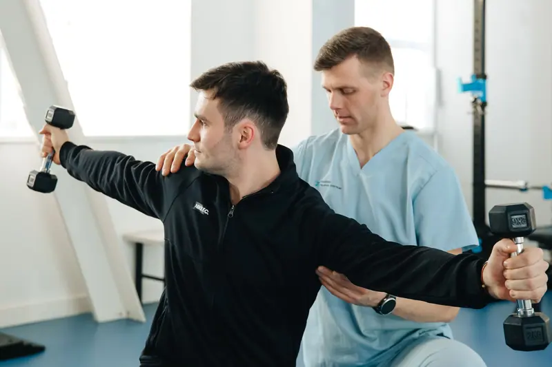 A therapist guiding a guest through a dumbbell exercise
