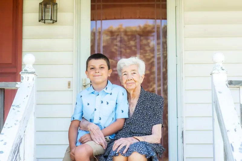 A grandmother and grandson sitting together on the front porch