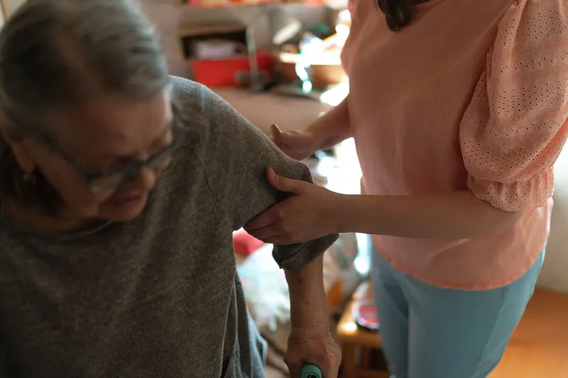 A therapist steadying a resident as she practices standing from her chair