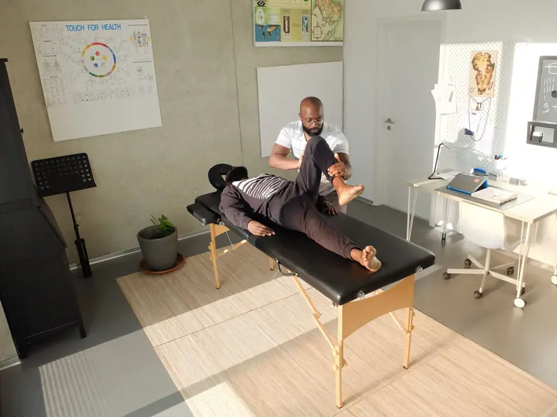 A therapist treating a patient on the table in a sunny treatment room