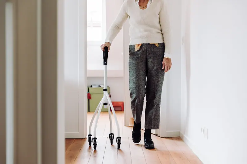 A patient practicing with her quad cane down the hallway