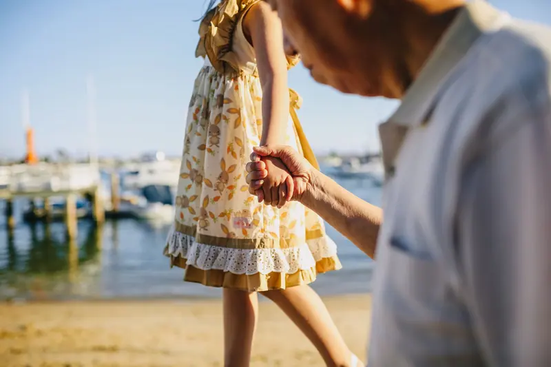 A grandfather helping his granddaughter keep her balance on the waterfront