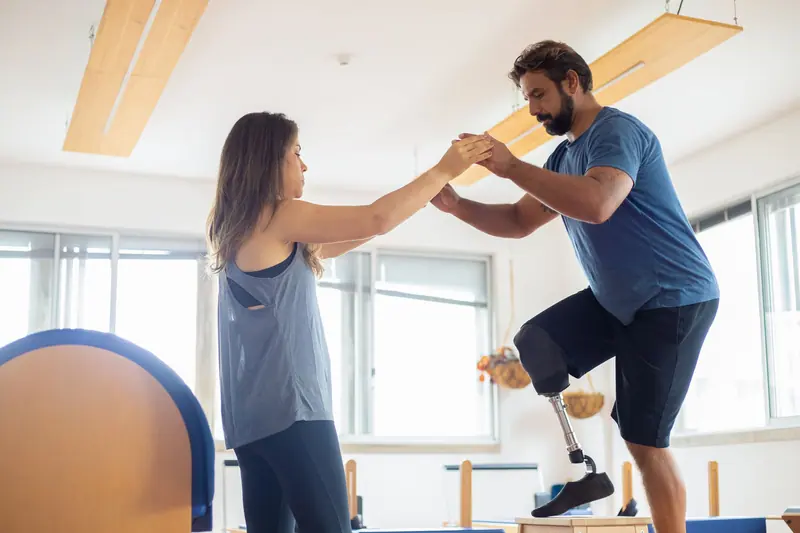 A therapist steadying a patient as he climbs a practice step