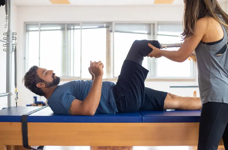 A therapist guiding a guest's leg on the reformer
