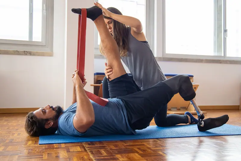 A therapist using a strap to stretch a patient's leg