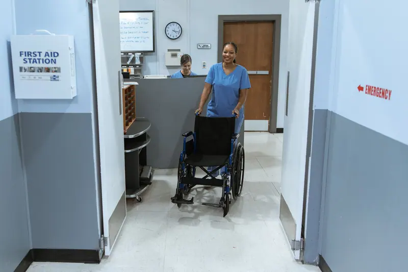 A nurse wheeling a guest down the hall