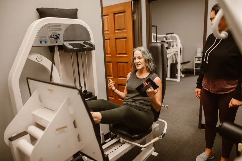 A patient on the leg press as her therapist coaches