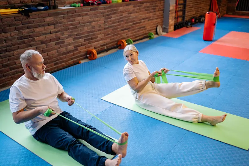 Two patients working with resistance bands on the gym mats