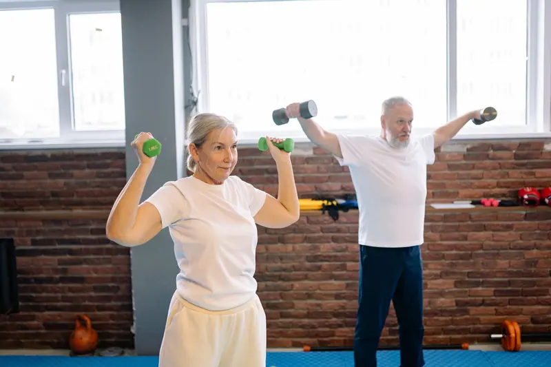A couple working with light dumbbells in the exercise room