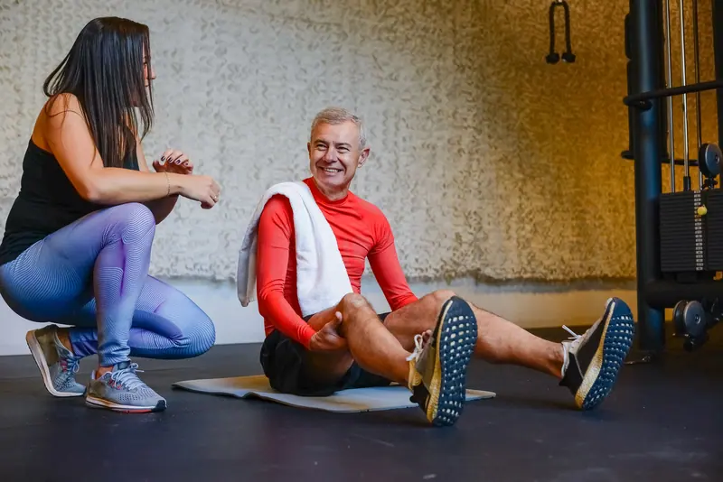 A therapist crouching beside a patient during floor exercises