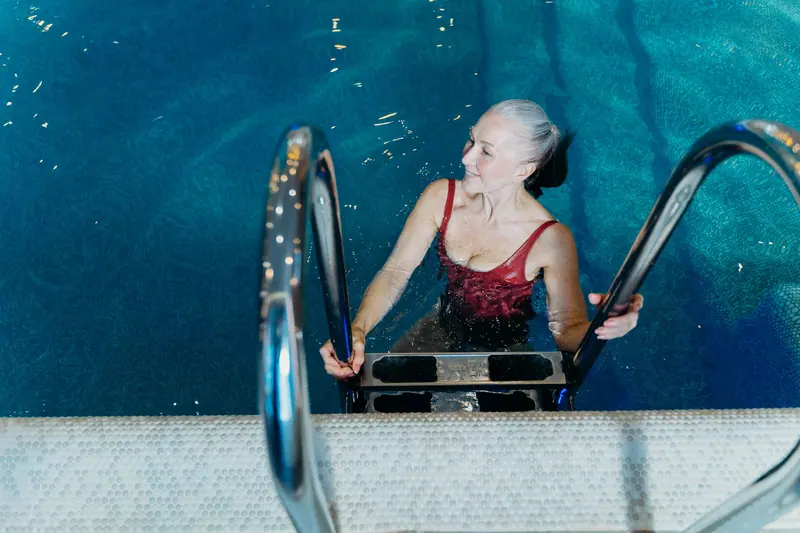 A patient stepping out of the warm-water therapy pool with a smile