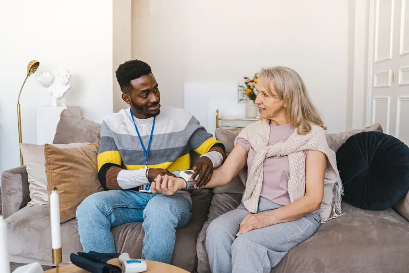 A nurse checking a patient's blood pressure in the lounge