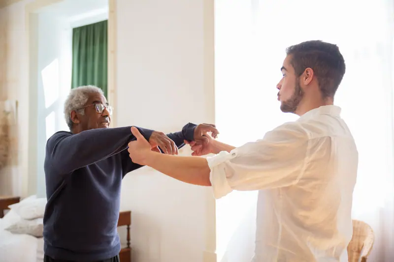 A therapist helping a guest raise his arms