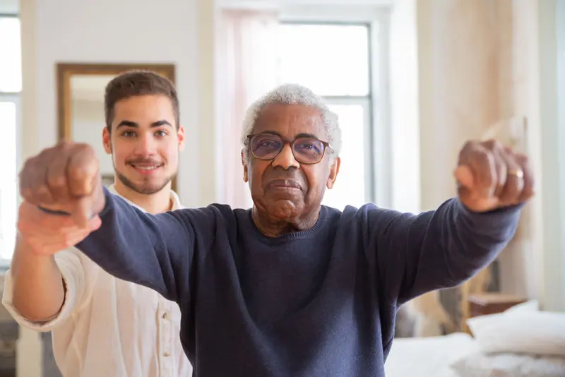 A guest stretching his arms with his therapist cheering him on